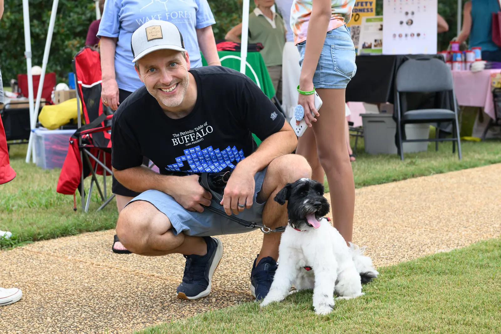 A visitor crouches beside his leashed terrier on a paved path at E. Carroll Joyner Park in Wake Forest.