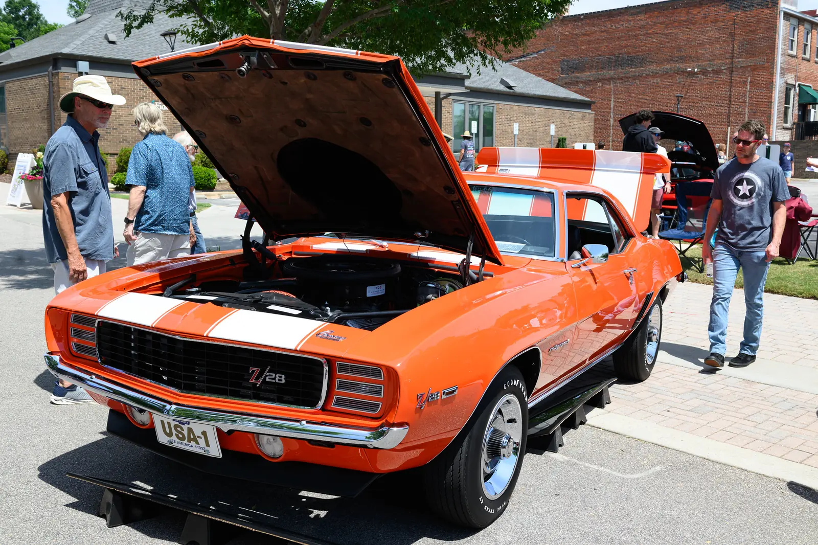 Visitors look over a classic orange Camaro at the Cars and Carnivores car show in downtown Wake Forest.