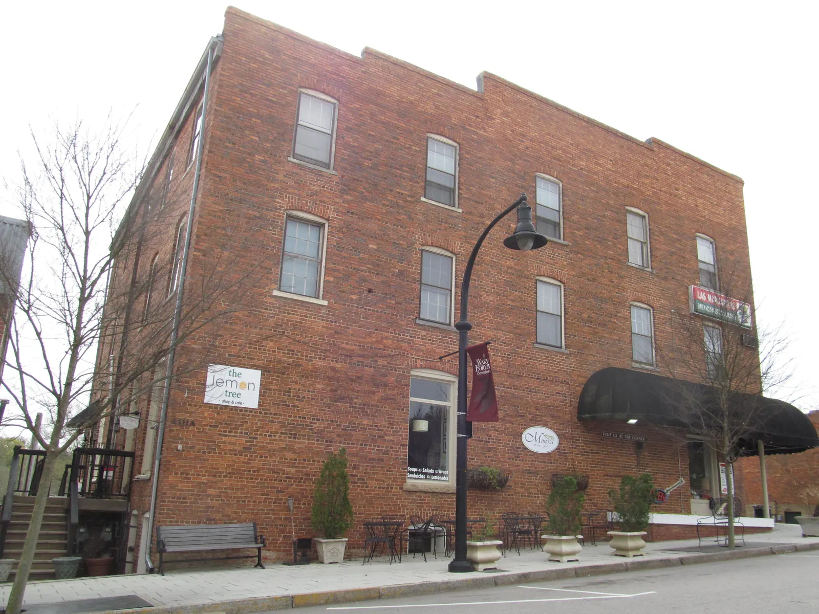 A brick building with a black awning and a street lamp banner in downtown Wake Forest.