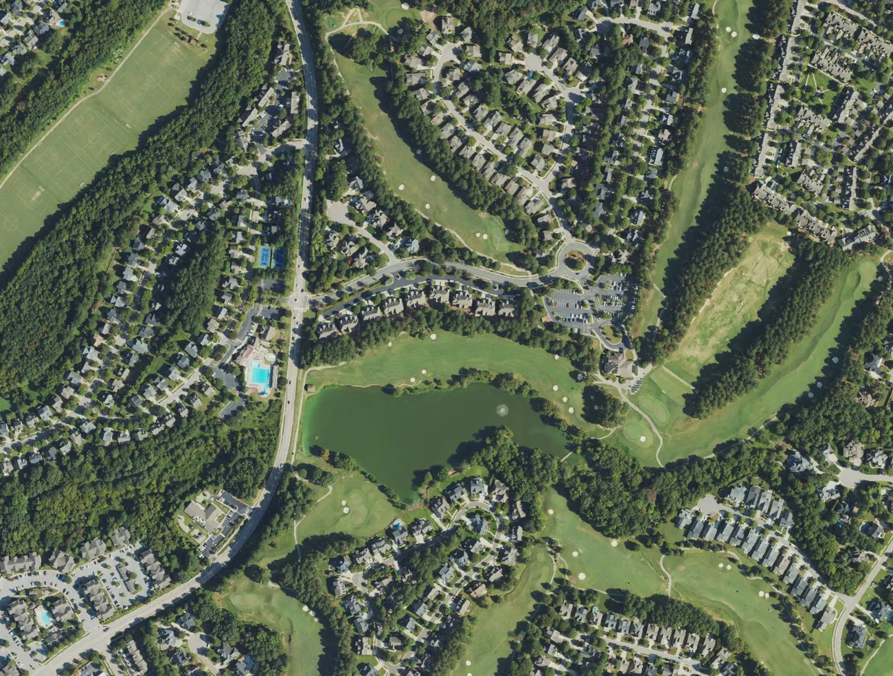 Aerial view of part of Heritage in Wake Forest, with homes and townhouses around a golf course and pond.