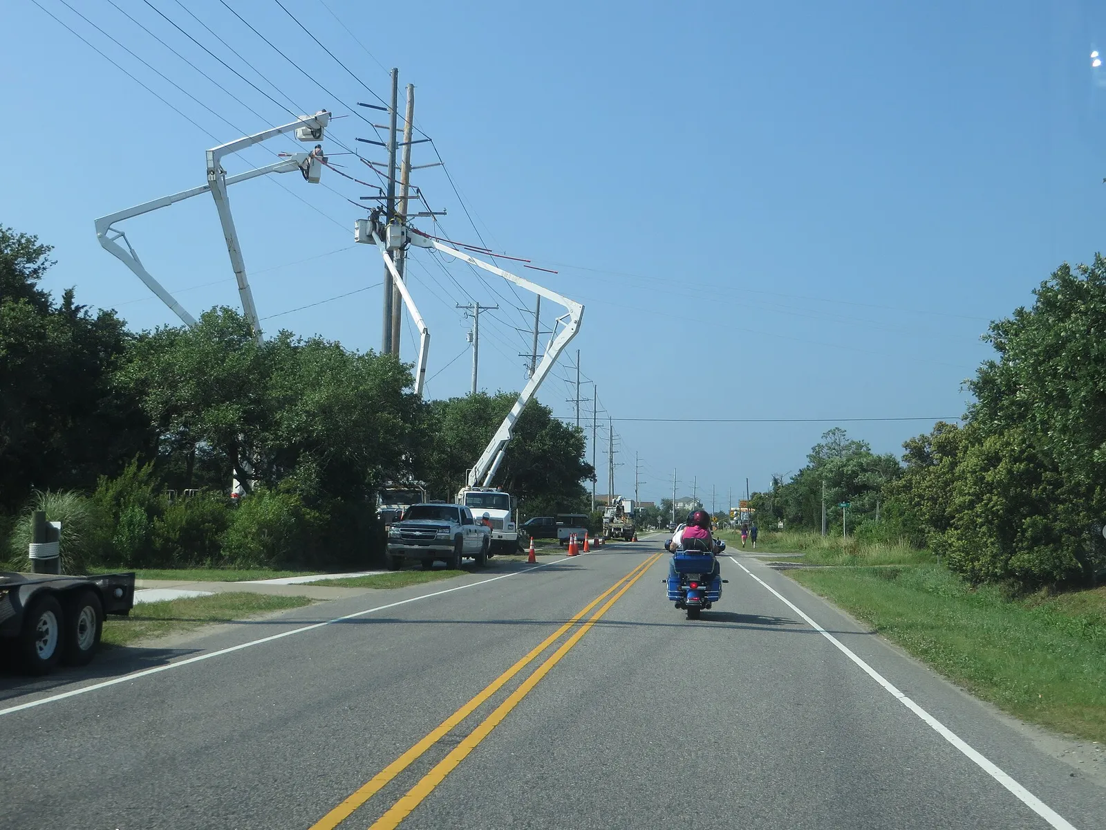 Line crews in bucket trucks work on power lines along a road in Salvo, on North Carolina's Outer Banks.