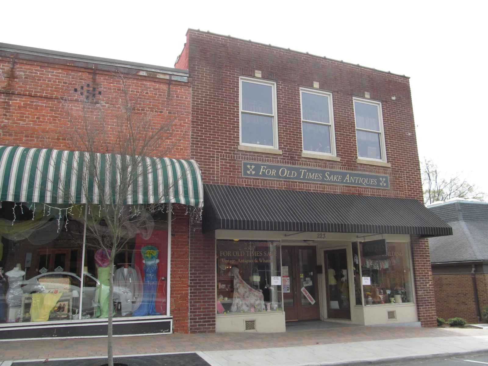 Brick storefronts with striped awnings in historic downtown Wake Forest, the business district the Spirits of Wake Forest ghost walks cover.